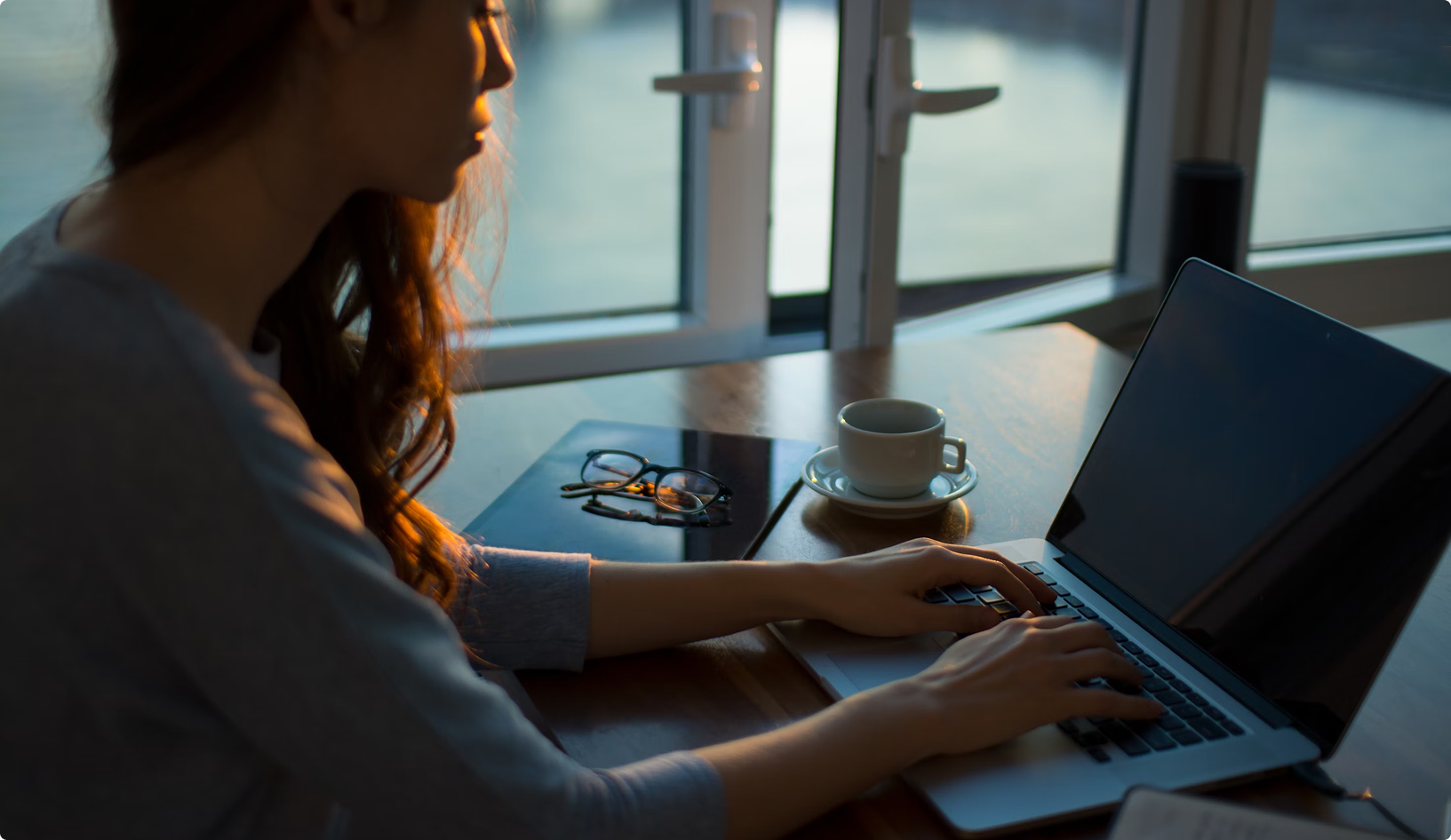 Writer working on laptop with coffee in warm lighting